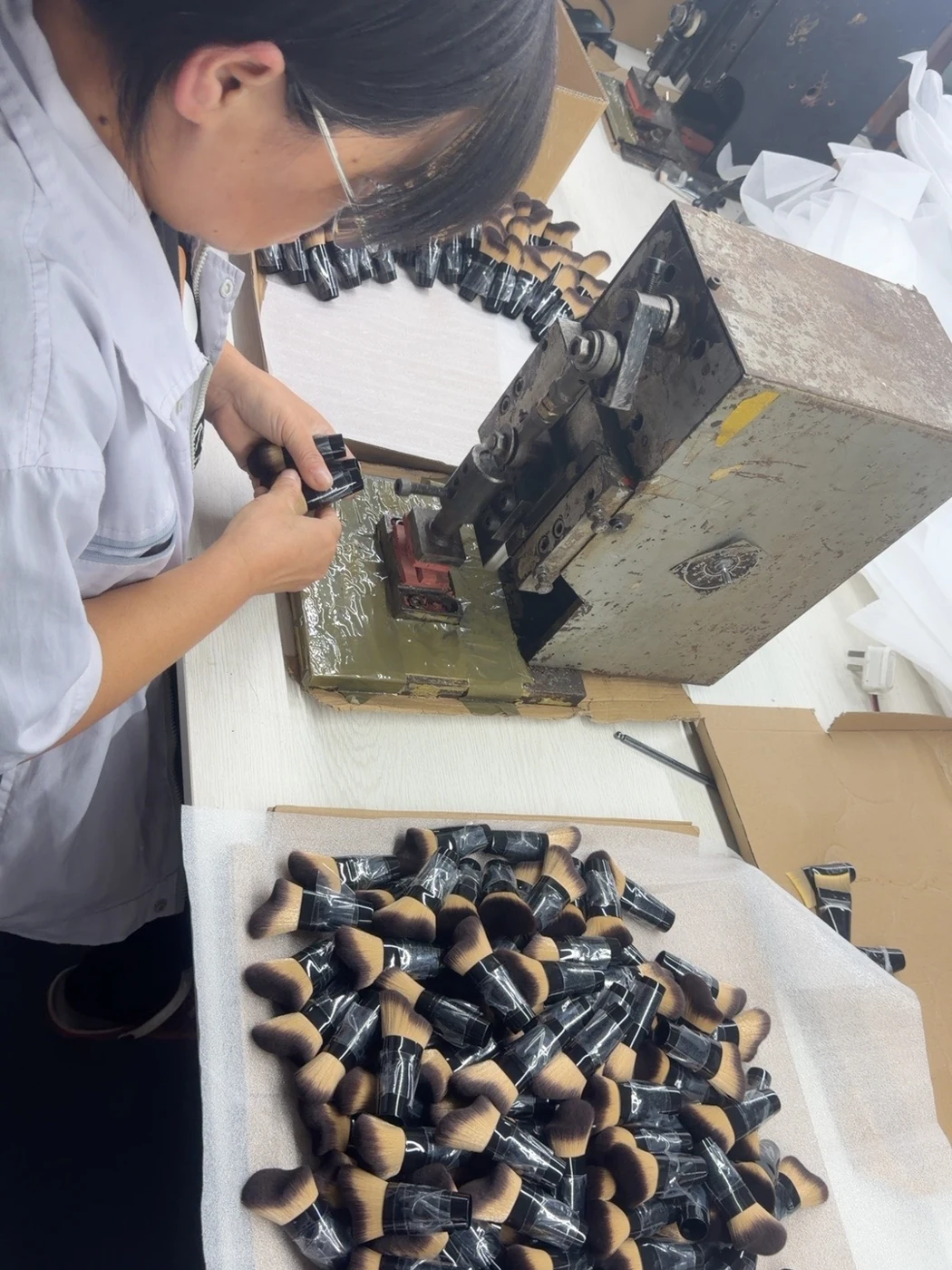 An operator positioning a brush head in a ferrule crimping tool