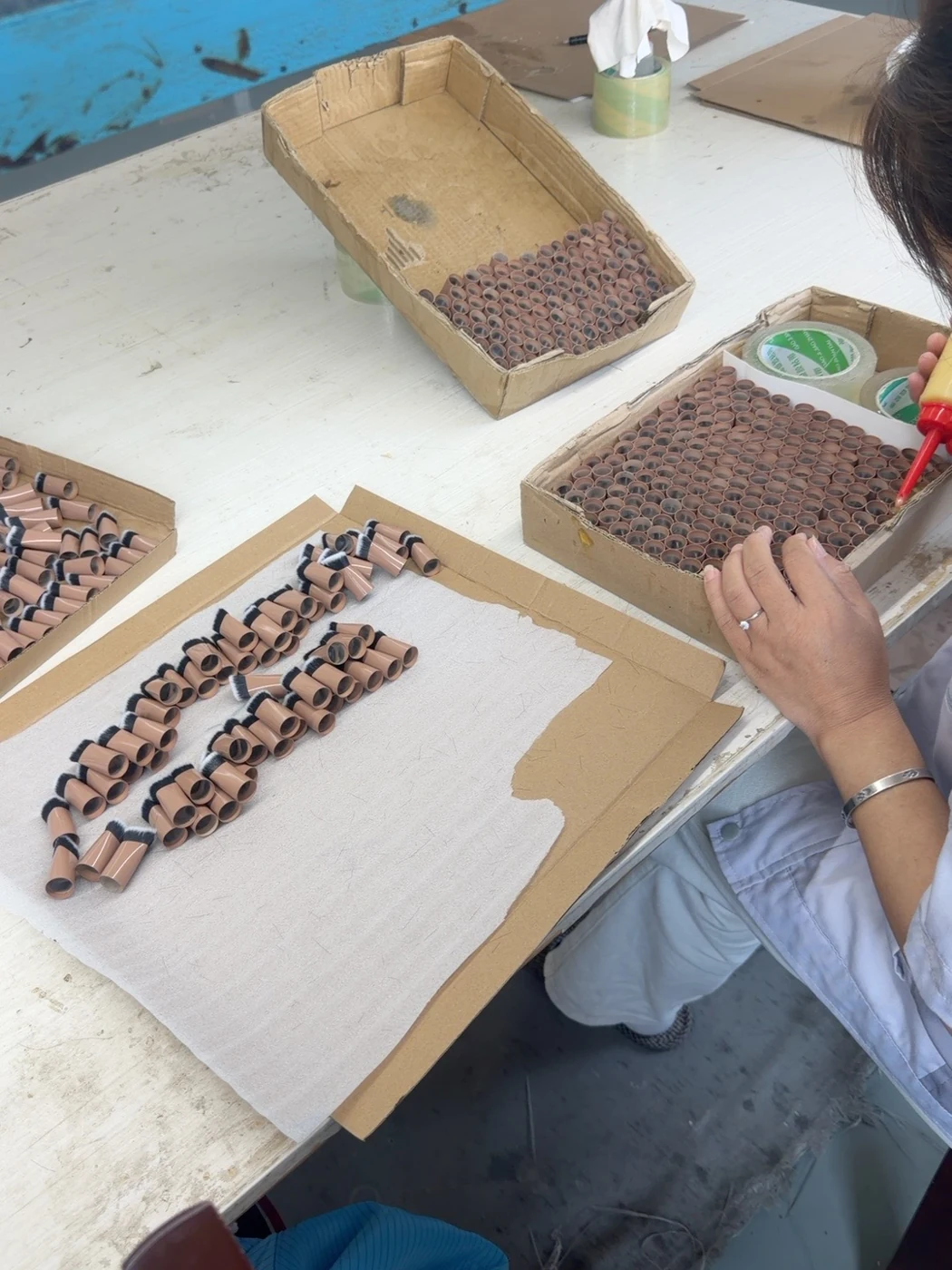 Adhesive being applied to brush head assemblies at a workbench