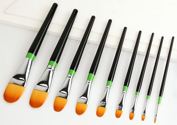 Black-handle art brushes with green bands and orange heads