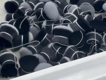 Loose round brush-head bundles beside stacked trays