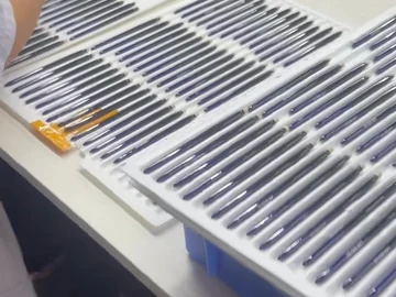 Operator beside trays of slim brush components
