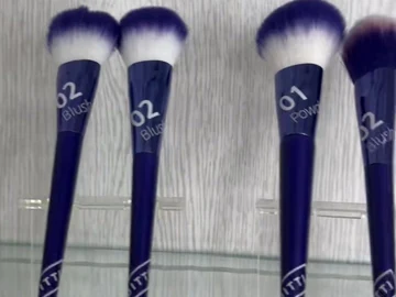 Blue-handle face brush samples on a display stand