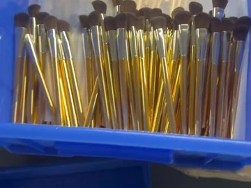 Sleeved gold-tone brushes in a blue bin