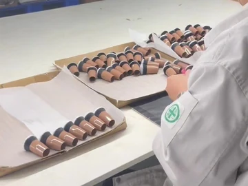 Operator handling a brush beside component trays