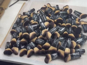 Black-and-gold compact brushes on a lined table