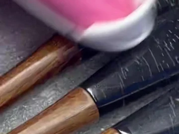 Pink-gloved hand beside brown-handle brushes