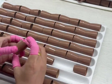 Hand work beside stacked brush-body trays