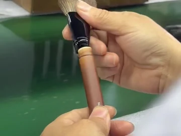 Long brown-handle brush held at the bench