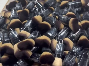 Black-and-gold brushes grouped below an open carton